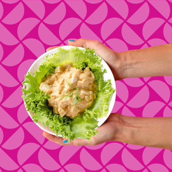 Two hands holding a bowl of Eggless Salad