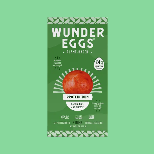 Front of a Wonder Eggs plant-based protein bun box, green packaging with a large red bun illustration and text reading 'Protein Bun' and the flavor 'Bacon, Egg, and Cheese'.